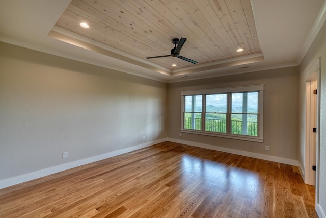 empty room with a tray ceiling, wooden ceiling, baseboards, crown molding, and light wood-type flooring