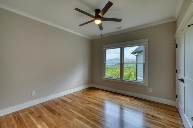 empty room featuring light wood-type flooring, visible vents, baseboards, and ornamental molding
