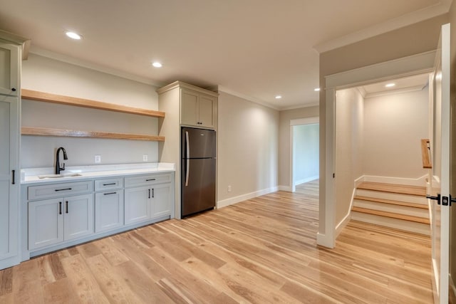 kitchen featuring a sink, freestanding refrigerator, ornamental molding, open shelves, and light wood-style floors