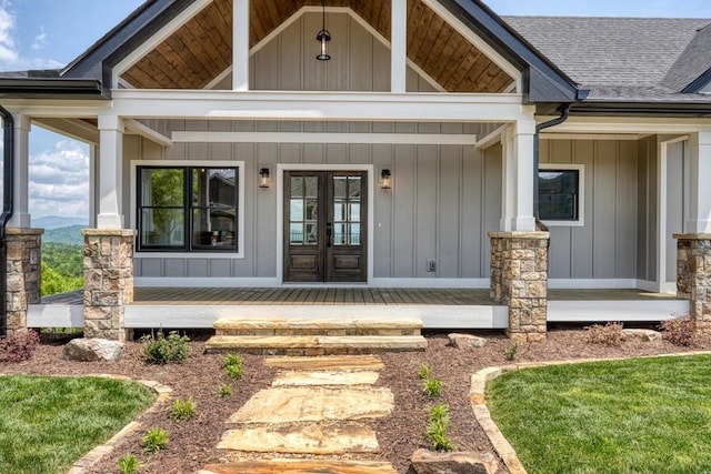 view of exterior entry with board and batten siding, roof with shingles, and french doors
