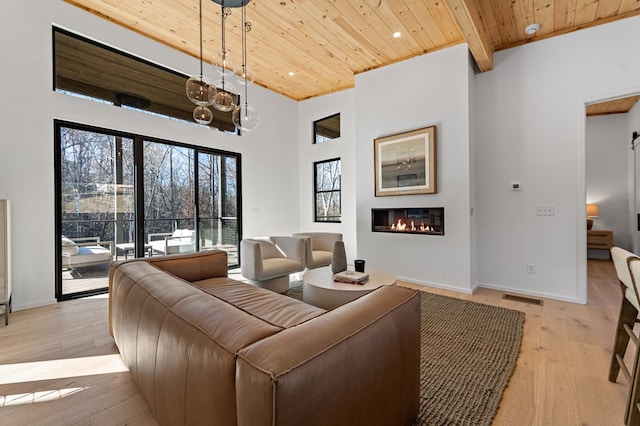 living room featuring a towering ceiling, wood ceiling, and light hardwood / wood-style floors