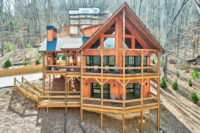 exterior space with a wooden deck, a wooded view, and a chimney