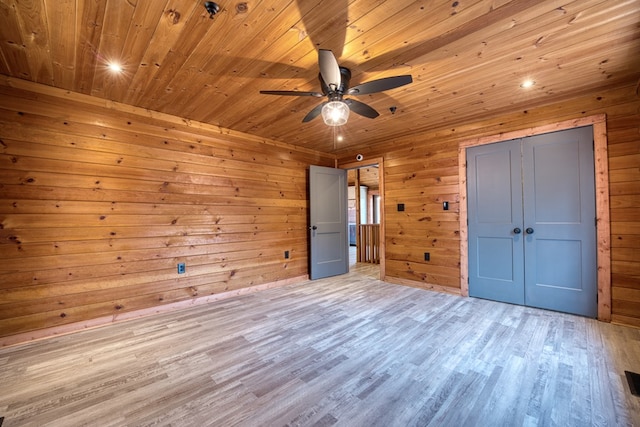 unfurnished bedroom with wood walls, light hardwood / wood-style flooring, and ceiling fan