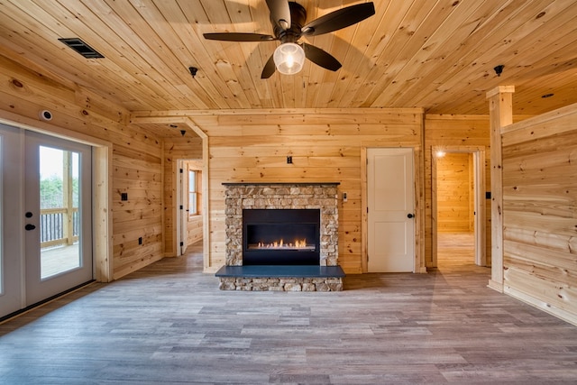 unfurnished living room with a stone fireplace, french doors, wood ceiling, and wood-type flooring