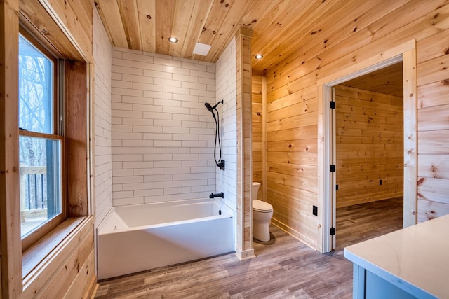 bathroom featuring tiled shower / bath combo, wooden ceiling, hardwood / wood-style floors, toilet, and wood walls