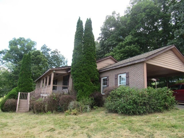 view of property exterior with a yard, covered porch, and a carport