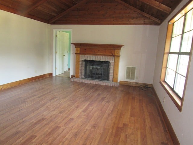 unfurnished living room featuring lofted ceiling with beams, a healthy amount of sunlight, and wood-type flooring