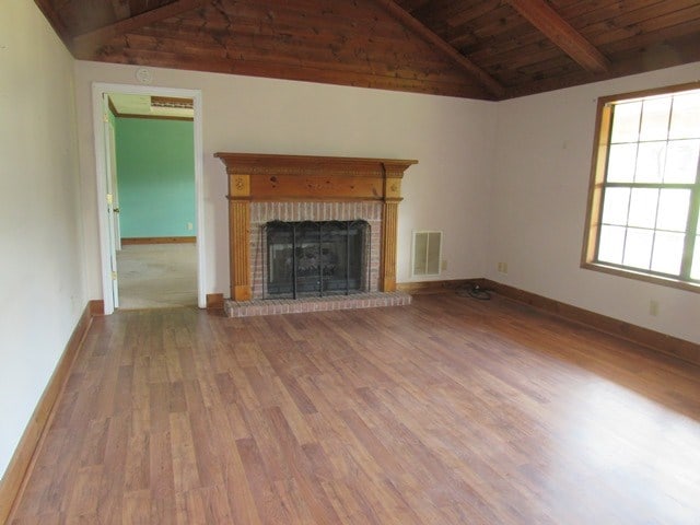 unfurnished living room with a fireplace, hardwood / wood-style floors, lofted ceiling with beams, and wood ceiling