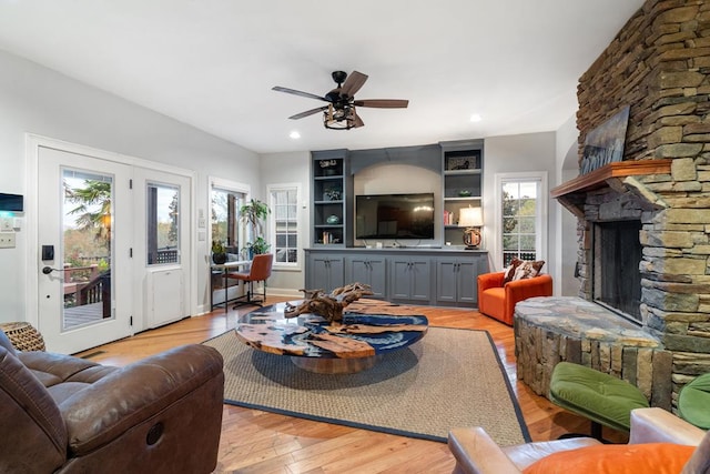 living room with a fireplace, light hardwood / wood-style flooring, and ceiling fan