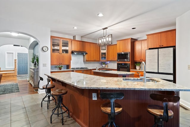 kitchen featuring black appliances, sink, a large island, a breakfast bar, and pendant lighting