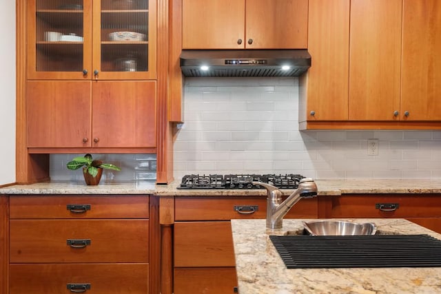 kitchen featuring tasteful backsplash, ventilation hood, light stone countertops, and stainless steel gas stovetop