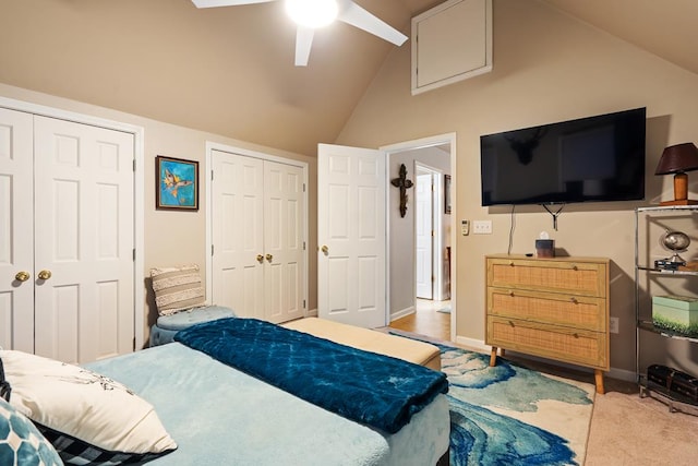 bedroom featuring ceiling fan, light carpet, multiple closets, and high vaulted ceiling