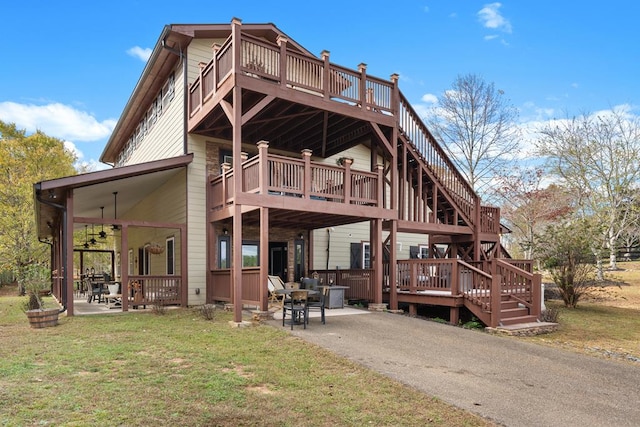 back of house with a deck, ceiling fan, a yard, and a patio