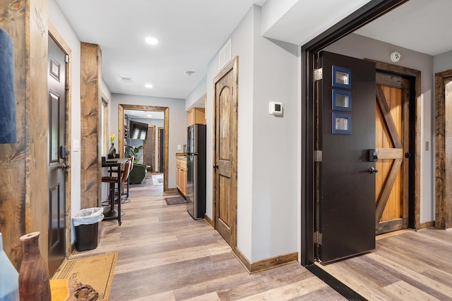 corridor featuring a barn door and light hardwood / wood-style flooring