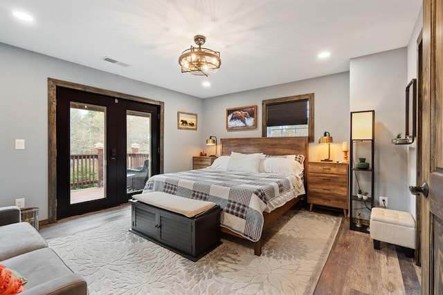 bedroom with french doors, access to outside, hardwood / wood-style flooring, and a chandelier