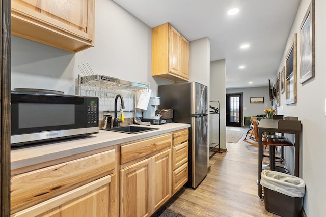 kitchen with light wood-type flooring, light brown cabinets, sink, and stainless steel appliances