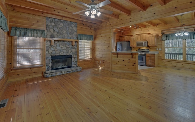 unfurnished living room featuring beamed ceiling, a stone fireplace, light hardwood / wood-style floors, and wood walls