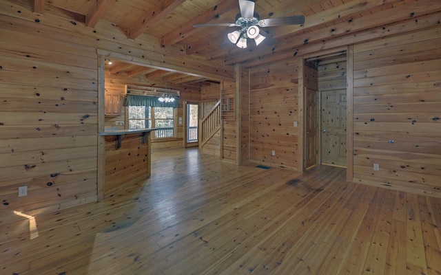 unfurnished room with wood walls, wood ceiling, wood-type flooring, beam ceiling, and ceiling fan with notable chandelier