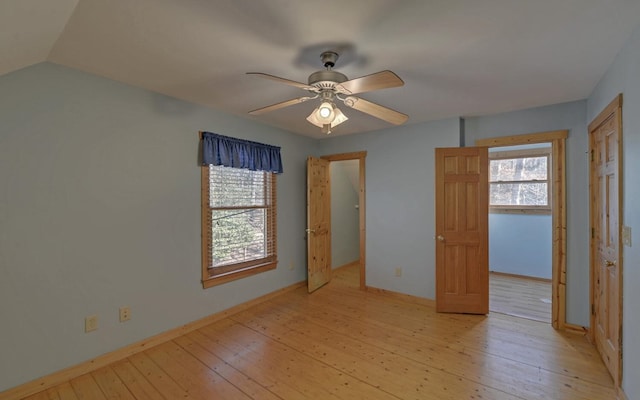 unfurnished bedroom featuring multiple windows, light hardwood / wood-style floors, ceiling fan, and lofted ceiling