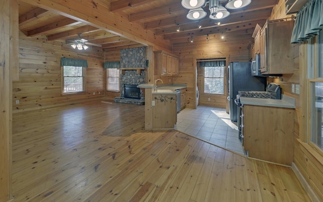 kitchen featuring a breakfast bar, wooden walls, gas range oven, and light wood-type flooring