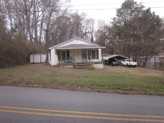 bungalow-style house with a porch, an outdoor structure, a shed, a front lawn, and a detached carport