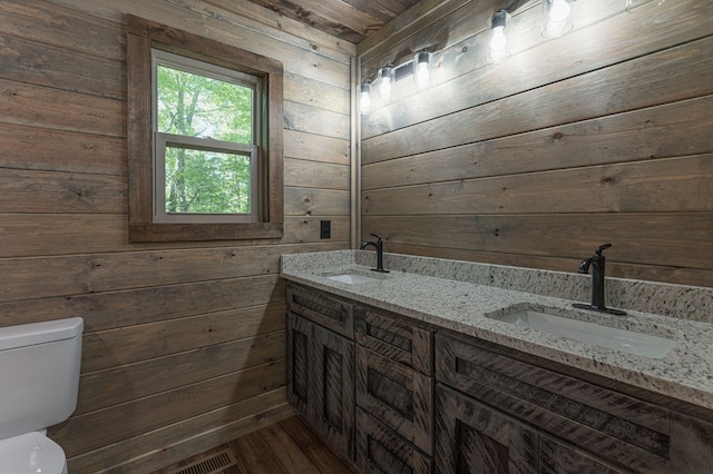 bathroom with wood walls, hardwood / wood-style flooring, vanity, and toilet