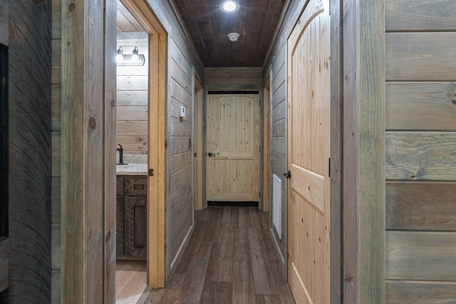 hallway featuring wood walls, sink, and dark wood-type flooring