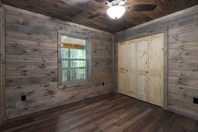 unfurnished bedroom featuring a closet, dark hardwood / wood-style flooring, wooden walls, wood ceiling, and ceiling fan