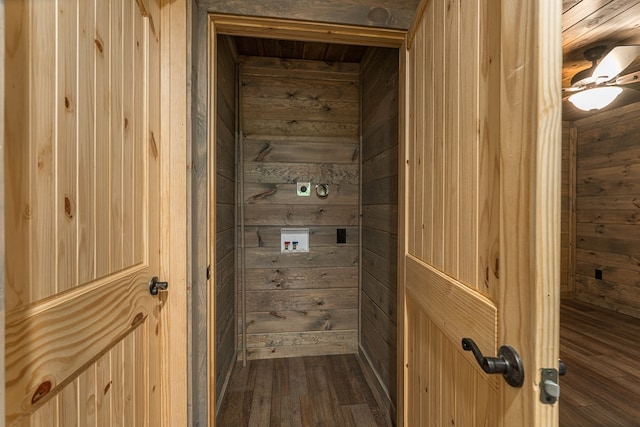 washroom with dark wood-type flooring, wood walls, and washer hookup