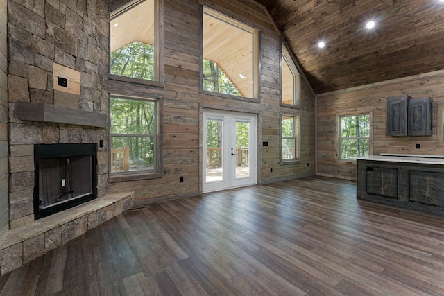 unfurnished living room with dark wood-type flooring, a stone fireplace, wooden walls, and high vaulted ceiling