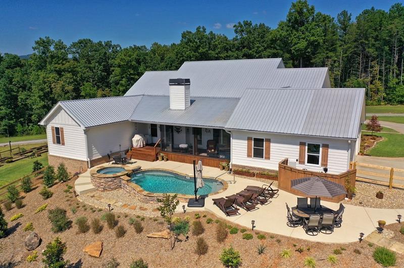 back of house featuring a swimming pool with hot tub and a patio area