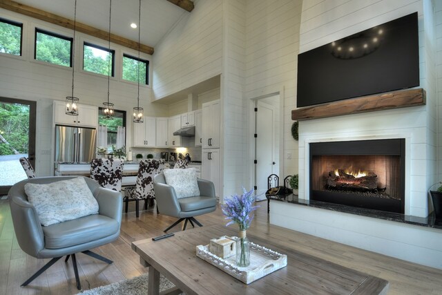 living room featuring beamed ceiling, high vaulted ceiling, and light hardwood / wood-style floors