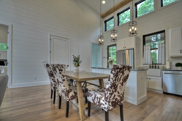 dining area with high vaulted ceiling, light hardwood / wood-style floors, and a notable chandelier