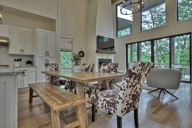 dining area with a high ceiling, wood-type flooring, a fireplace, and a chandelier