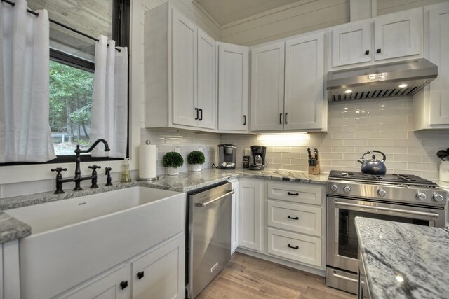 kitchen with exhaust hood, stainless steel appliances, and white cabinets