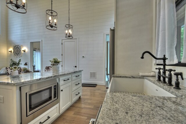 kitchen with pendant lighting, sink, light stone countertops, and stainless steel microwave