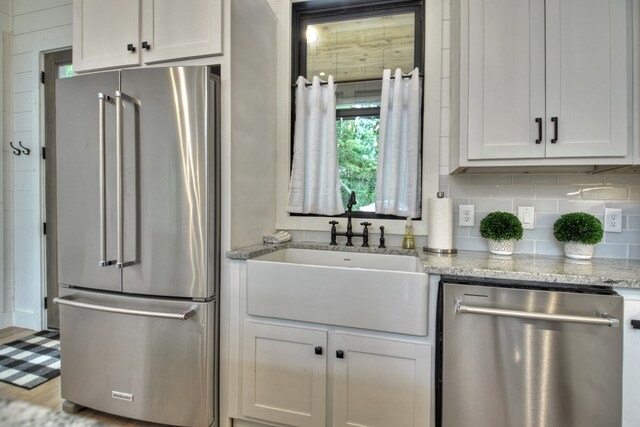 kitchen with sink, light stone counters, stainless steel appliances, and white cabinets