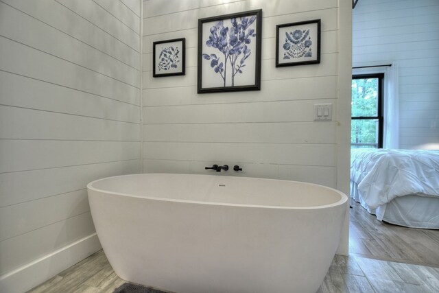 bathroom featuring a tub, wood-type flooring, and wooden walls