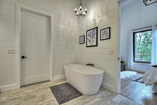 bathroom featuring a bath, a chandelier, and hardwood / wood-style flooring