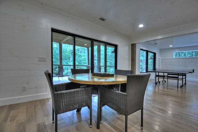 dining room with wood walls and light wood-type flooring