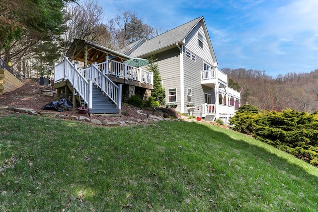 rear view of house featuring a wooden deck and a lawn