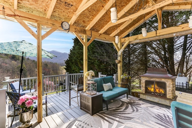 wooden terrace featuring a mountain view and an outdoor living space with a fireplace