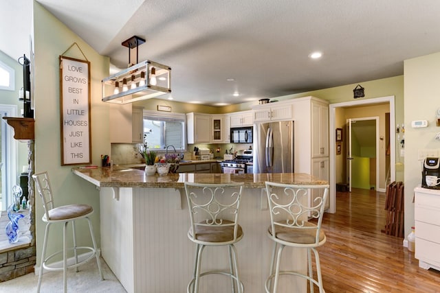 kitchen featuring a kitchen breakfast bar, light wood-type flooring, stainless steel appliances, and pendant lighting