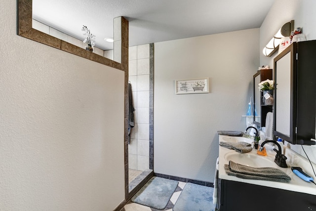 bathroom featuring vanity with extensive cabinet space, dual sinks, tile floors, and a tile shower