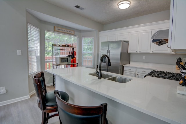 4149 Spring Cove Dr, Duluth, GA 30097 - kitchen with appliances with stainless steel finishes, a sink, premium range hood, light wood-type flooring, and a kitchen breakfast bar