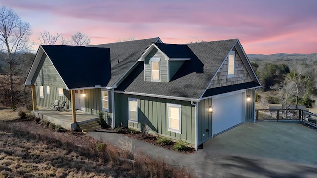 back house at dusk featuring a porch and a garage