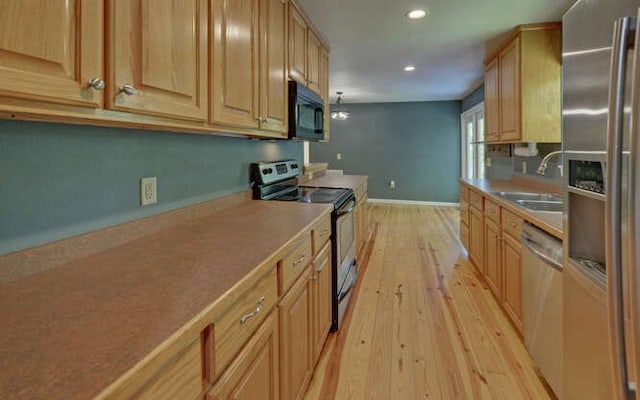 kitchen featuring appliances with stainless steel finishes, light wood-type flooring, a sink, baseboards, and recessed lighting