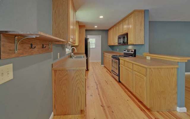 kitchen featuring light brown cabinetry, a sink, baseboards, light wood-style floors, and stainless steel appliances