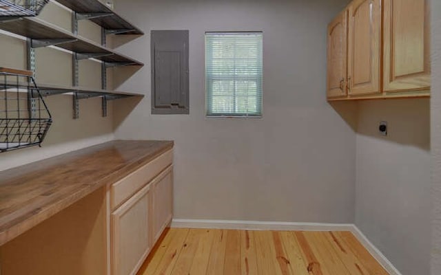 clothes washing area featuring light wood-style floors, baseboards, hookup for an electric dryer, and electric panel