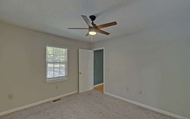 empty room featuring visible vents, a ceiling fan, baseboards, and light carpet